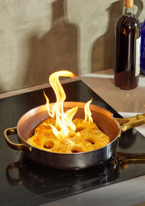 Pineapple slices up in flames in a chrome and gold Titanium Always Pan Pro