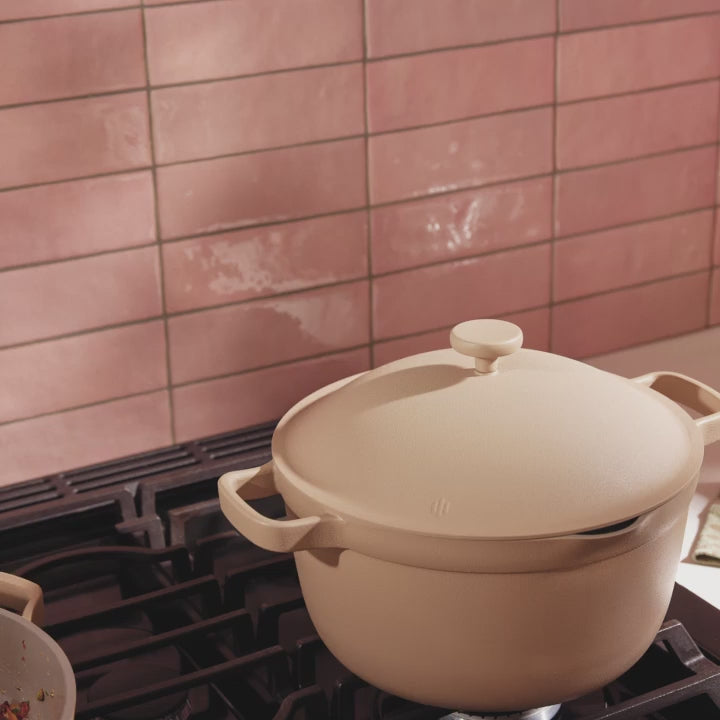 A chef pours oil and garnish over steaming cauliflower in a beige Perfect Pot, using a beige Always Pan