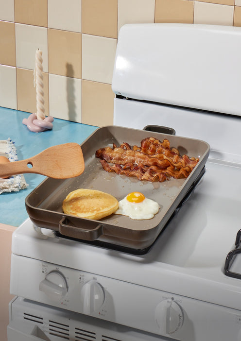 black griddle pan on stovetop with egg and bacon