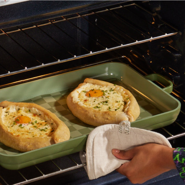 Green griddle pan in oven with garlic bread